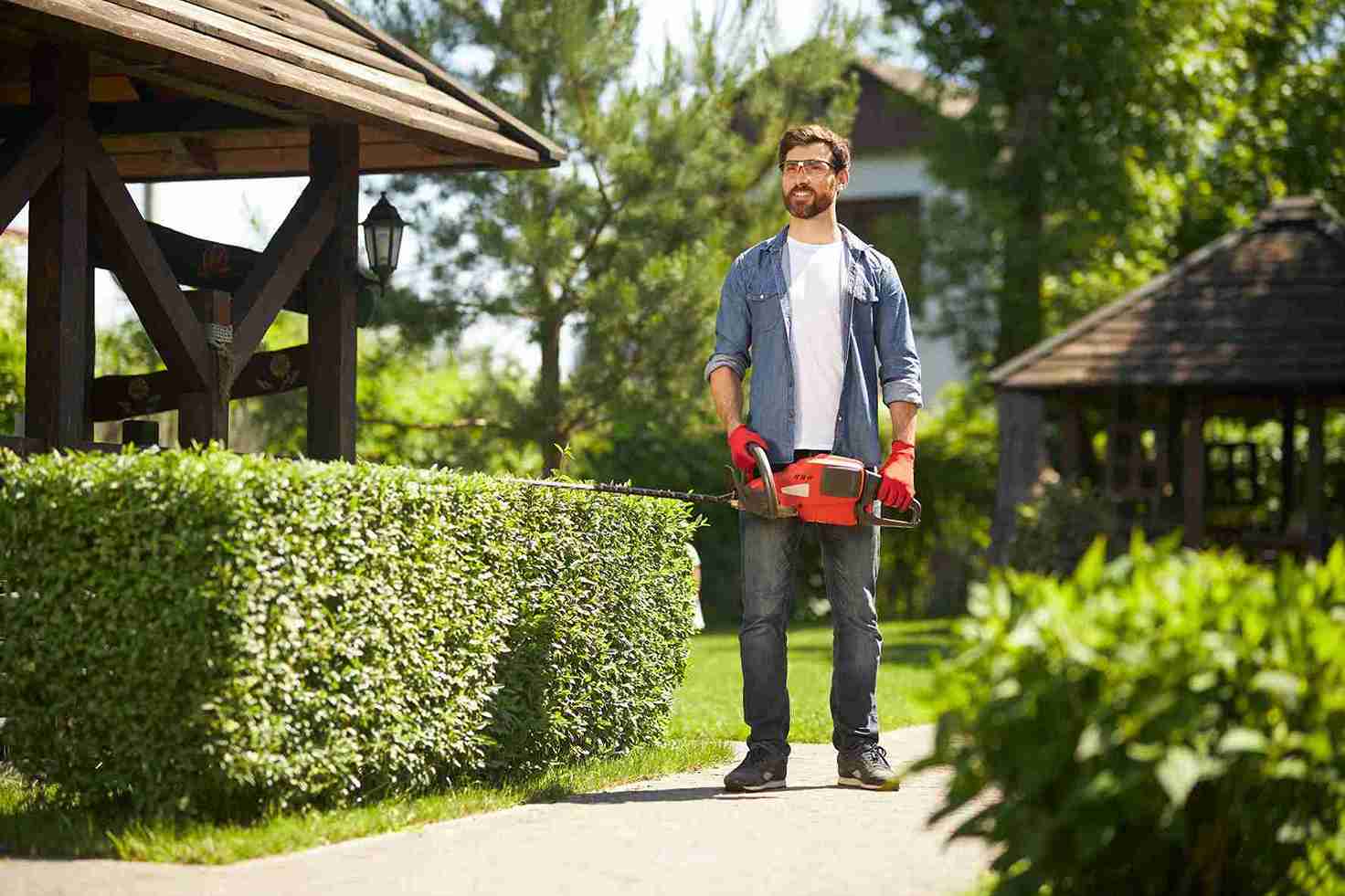 gardener-standing-carrying-modern-hand-hedge-trimmer-park-low-angle